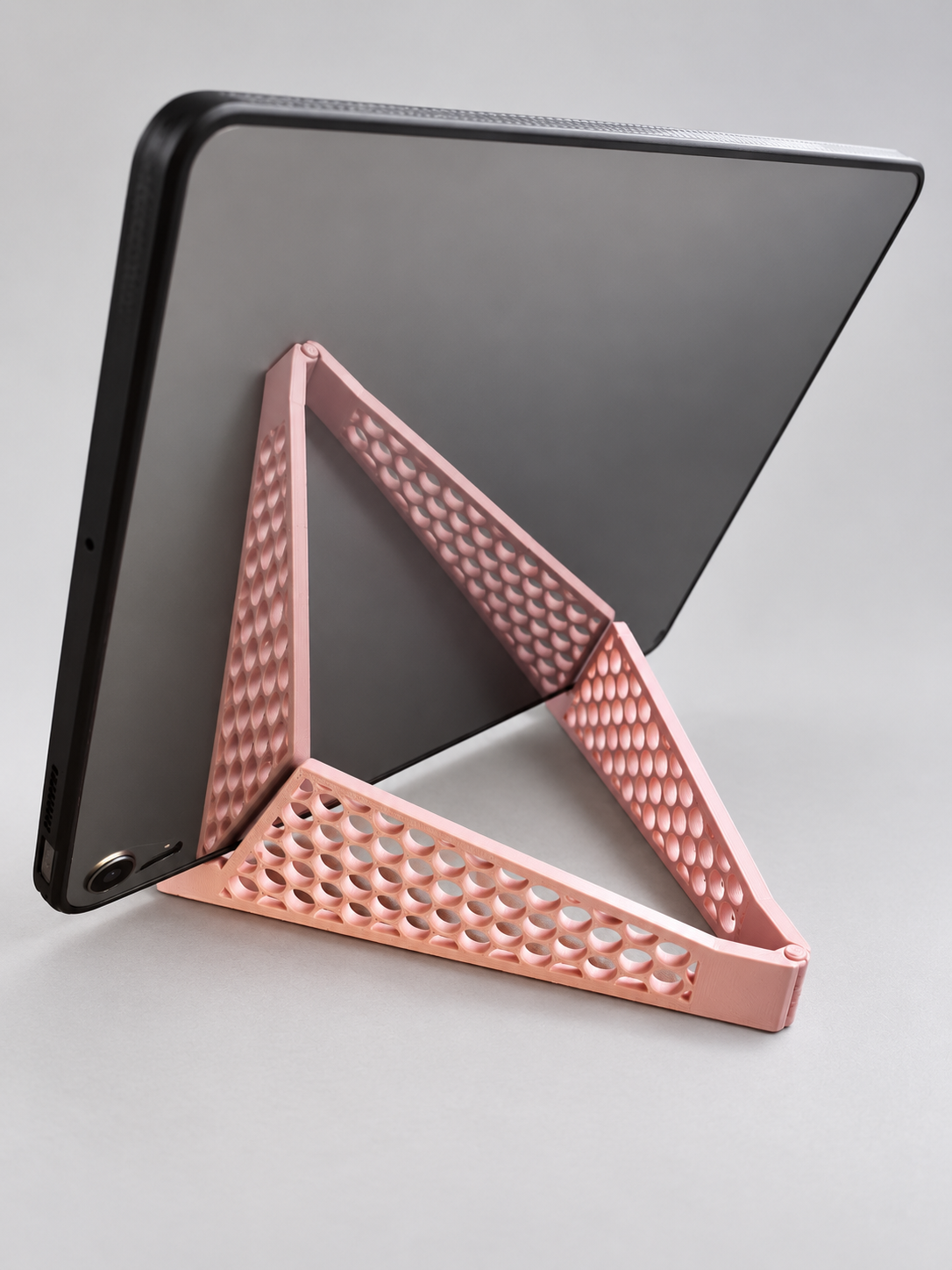 Pink perforated folding stand supporting a tablet